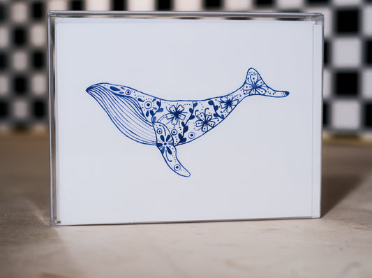 greeting card pack with a blue whale illustration design on a white background, against a black and white checkered wall.