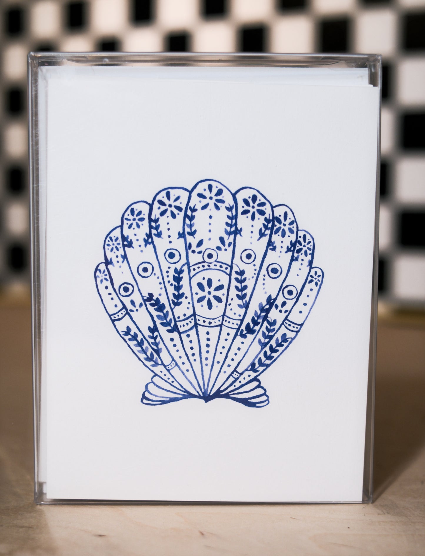 greeting card pack with a blue shell design design on a white background, against a black and white checkered wall.