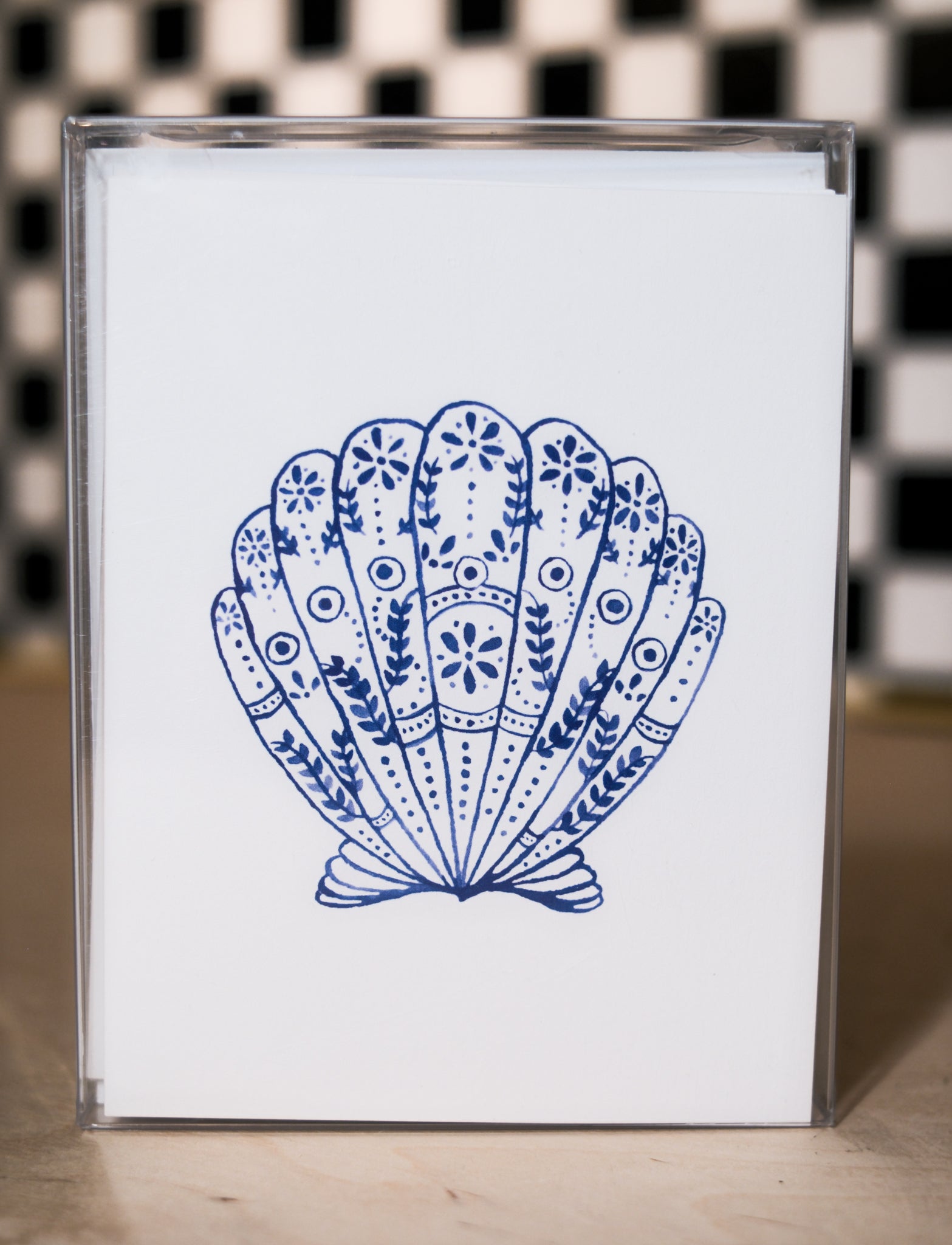 greeting card pack with a blue shell design design on a white background, against a black and white checkered wall.