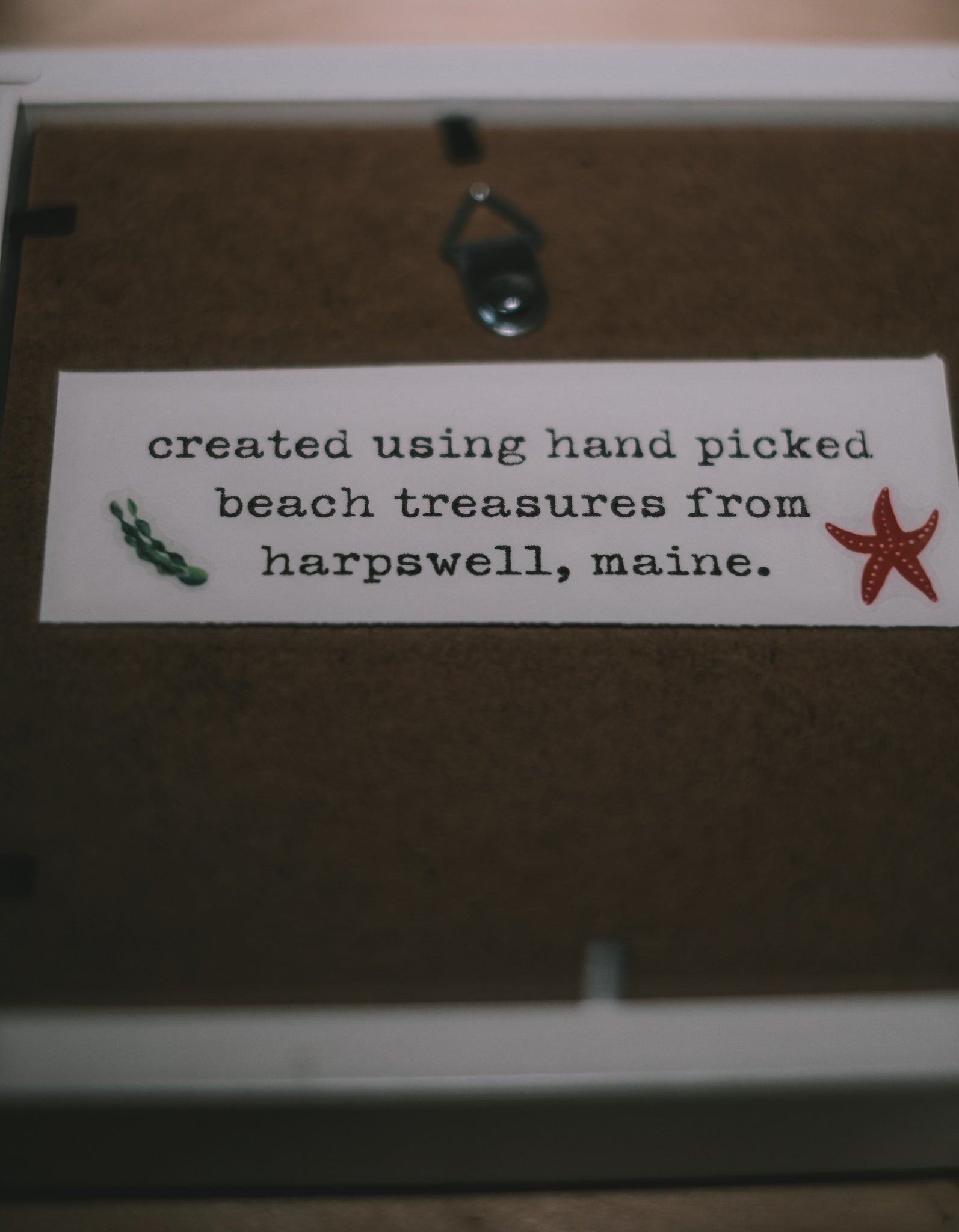 Label on a wooden surface with text 'created using hand picked beach treasures from harpswell, maine.'