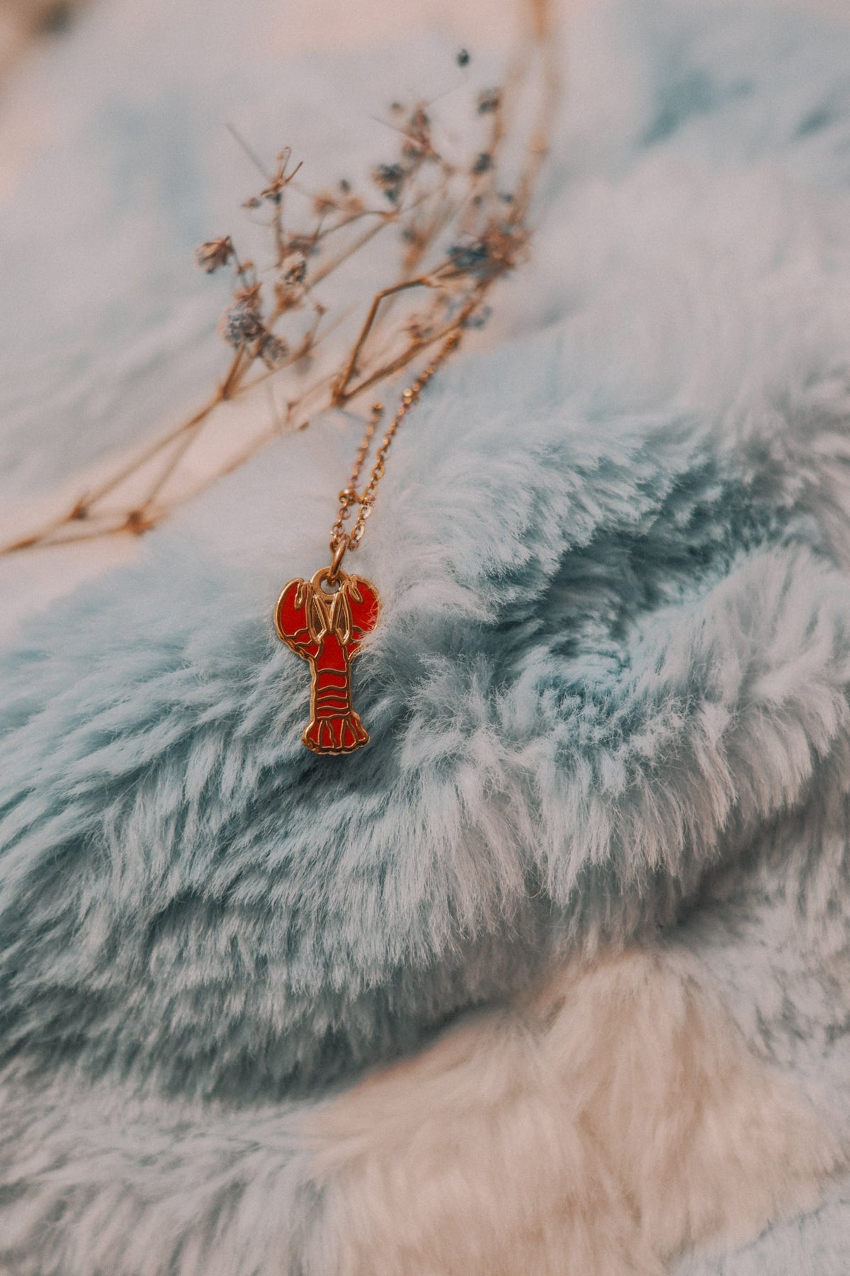 Necklace with a red lobster pendant on a blue textured surface