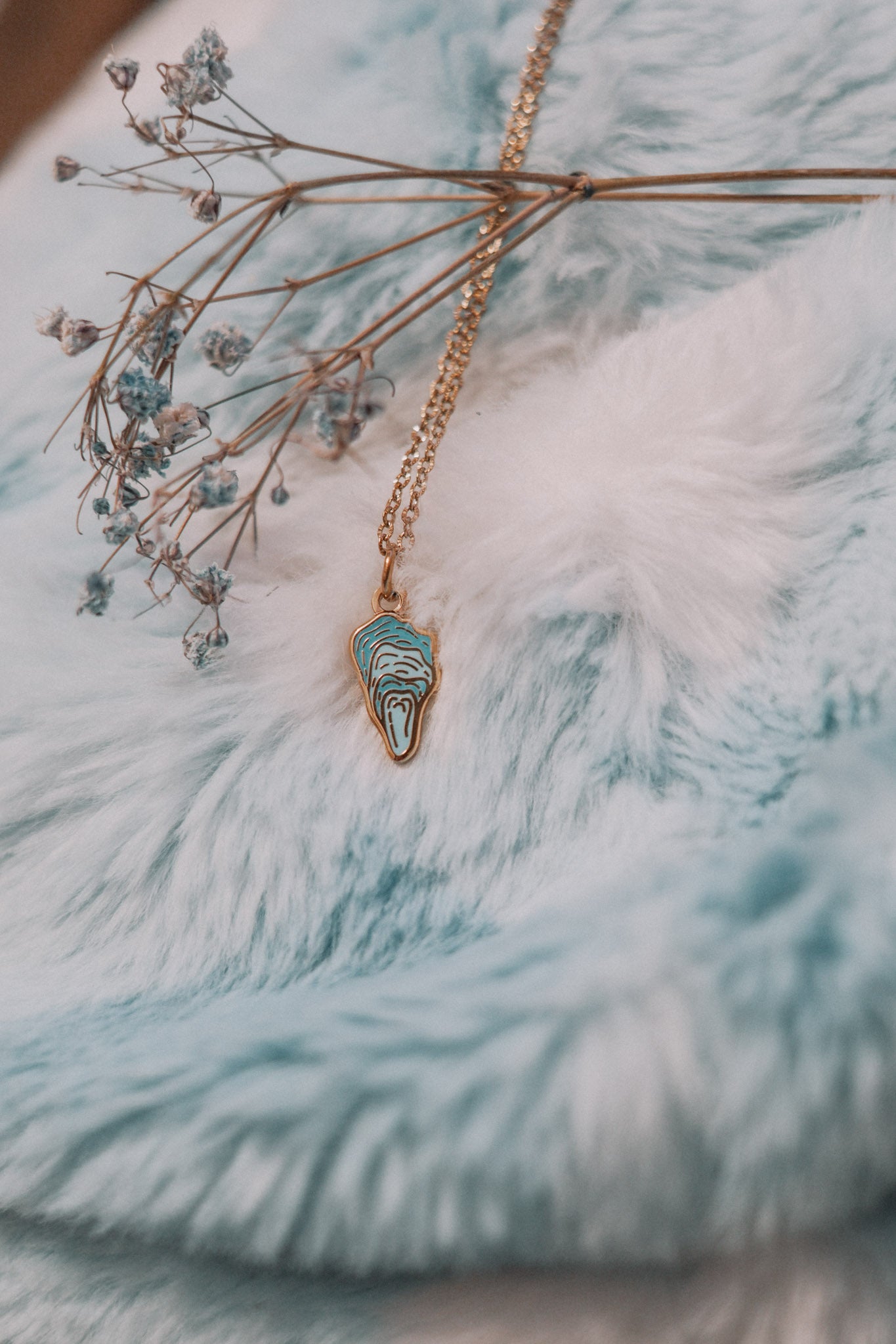 Necklace with a blue oyster pendant on a textured blue surface