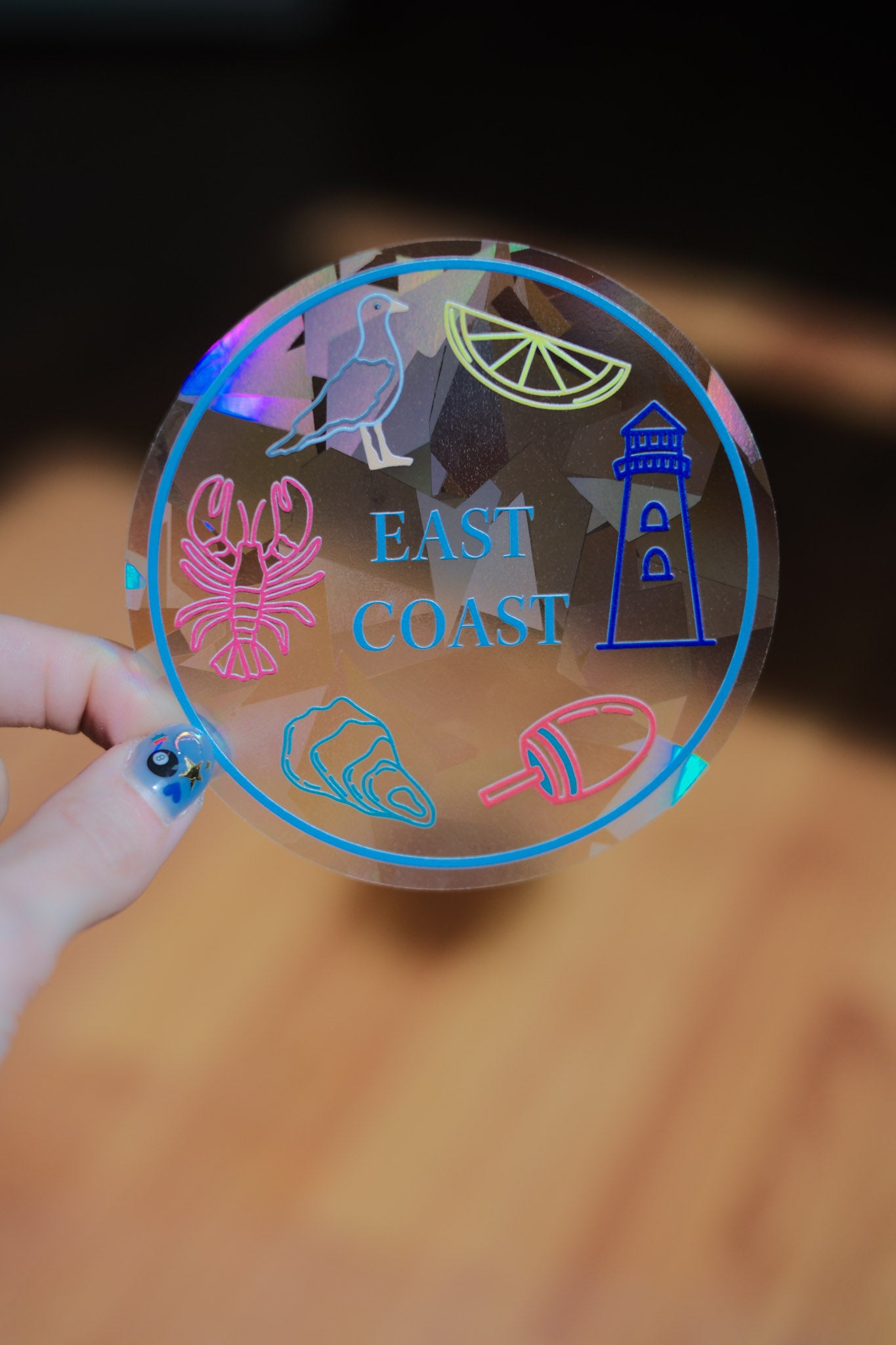 sun catcher reflective decal with colorful East Coast-themed designs held by a hand.