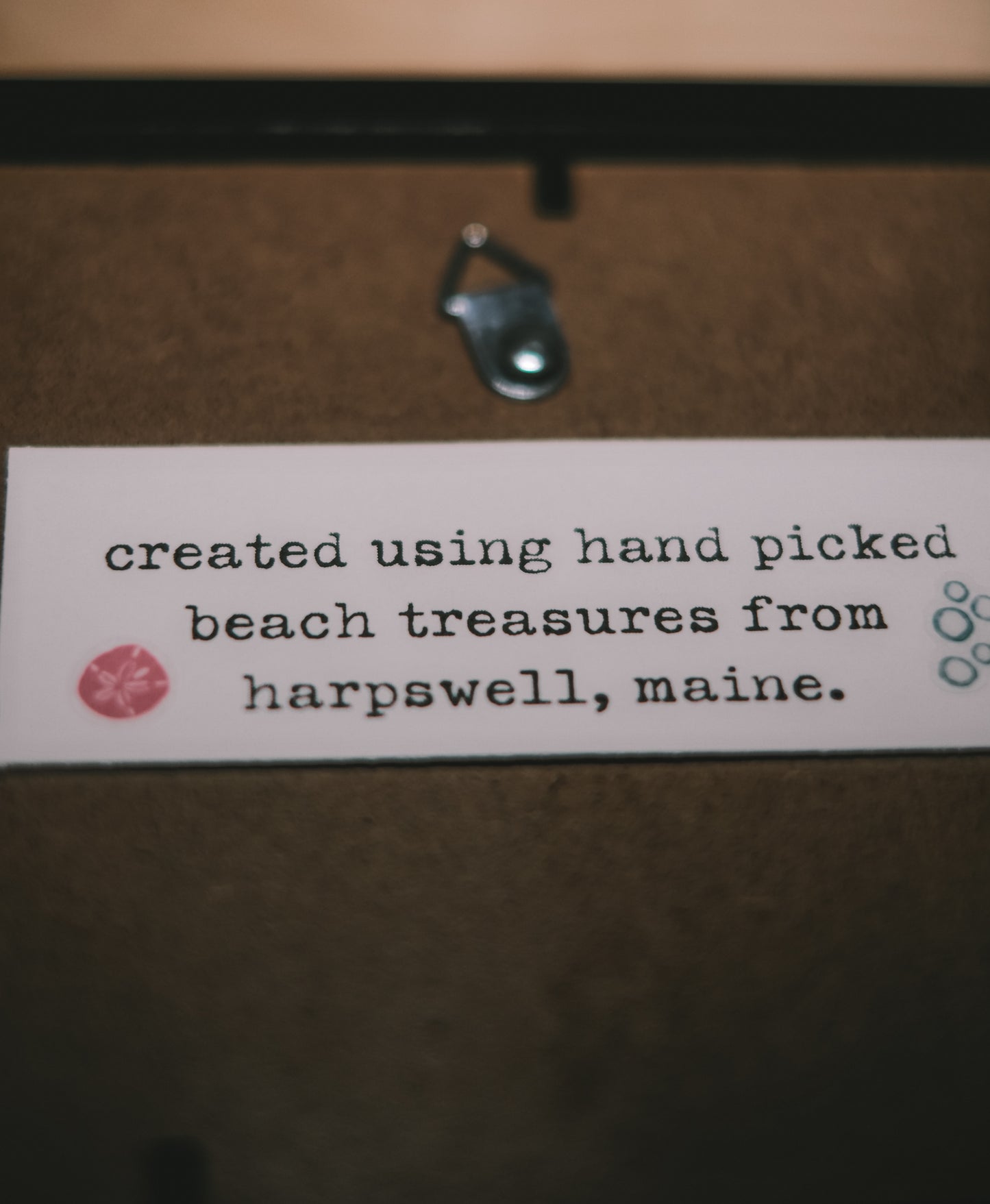 Text label on a wooden surface with 'hand picked beach treasures from Harpswell, Maine' text.