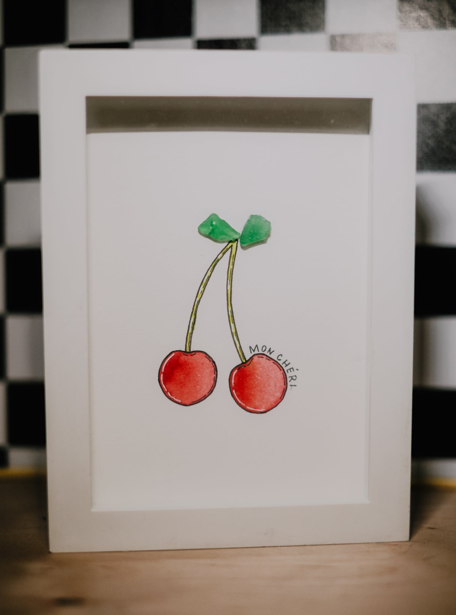 Framed illustration of cherries on a checkered floor background stating 'mon cheri'