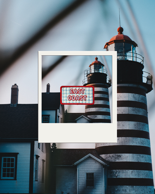 A iron on patch featuring blue and white gingham with red text 'EAST COAST' overlaid on a lighthouse scene which is  overlaid on a larger background photo of the same lighthouse.