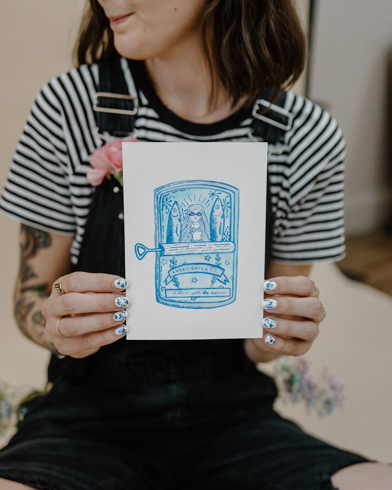 Person holding a card with a blue illustration of an open suitcase on a blurred background