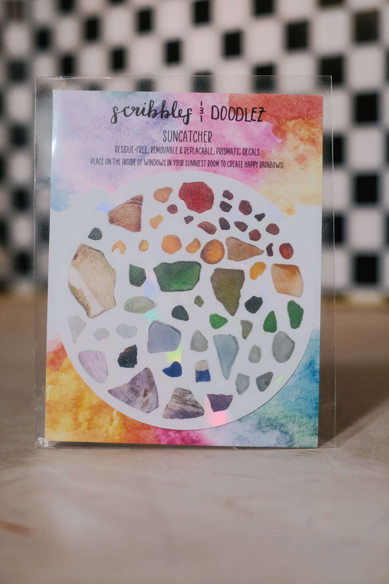 Colorful sun catcher decal with geometric shapes on a clear stand against a checkered background