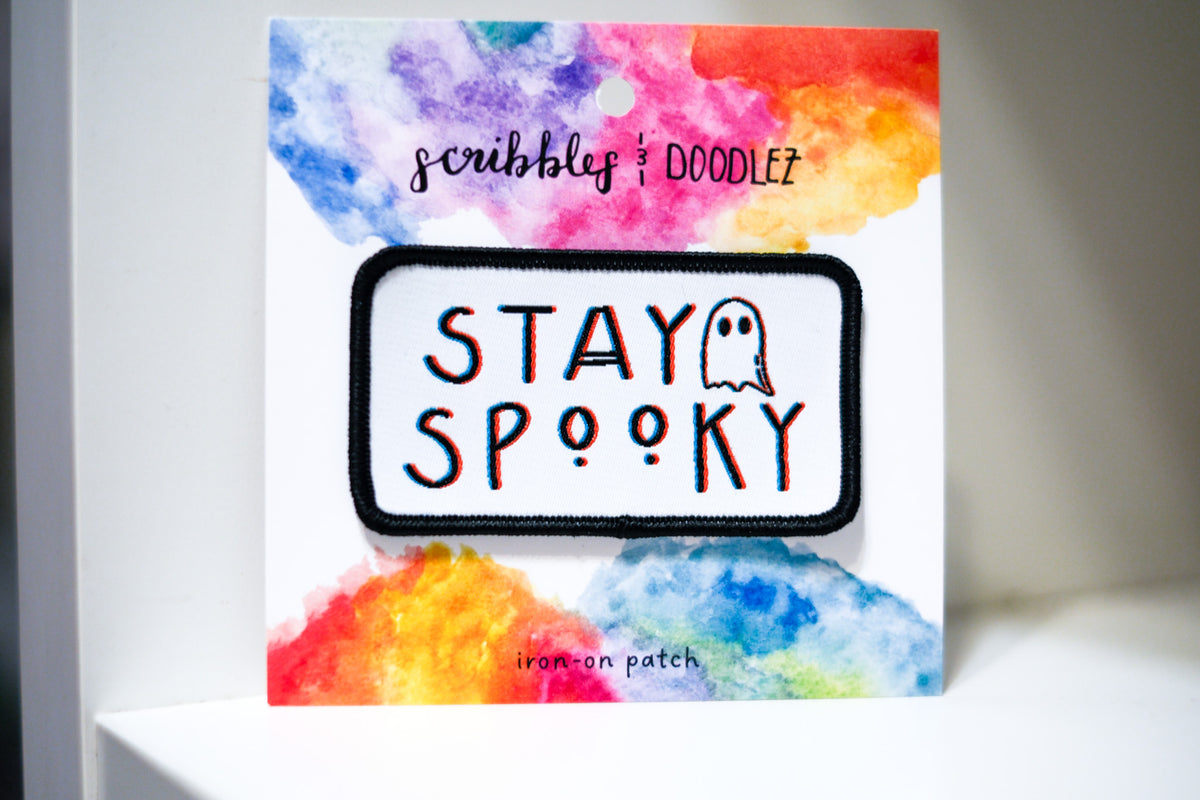 Stay Spooky iron-on patch with black lettering and ghost illustration on colorful 'Scribbles and Doodlez' packaging.