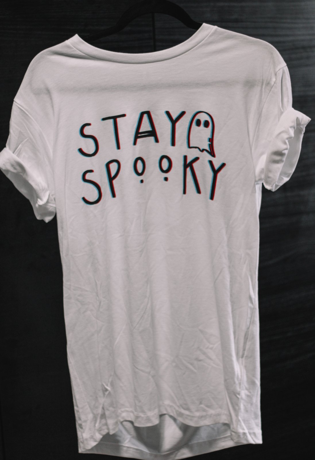 A white t-shirt that reads 'Stay Spooky' with a ghost in black, blue, and red text that creates a 3D look.
