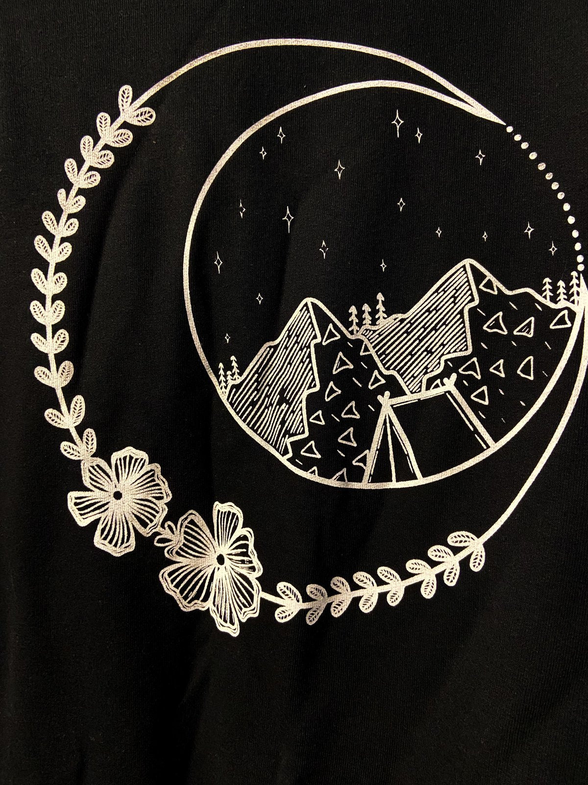 White design on black background, featuring crescent moon, flowers, mountain, and a tent.