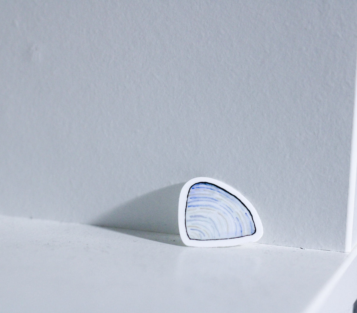 Photo of a watercolor periwinkle clam shell sticker on a white background.