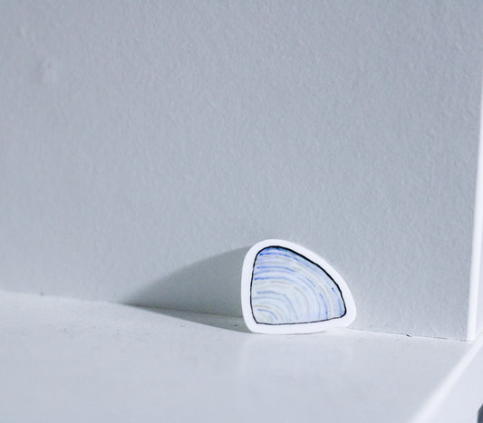 Photo of a watercolor periwinkle clam shell sticker on a white background.