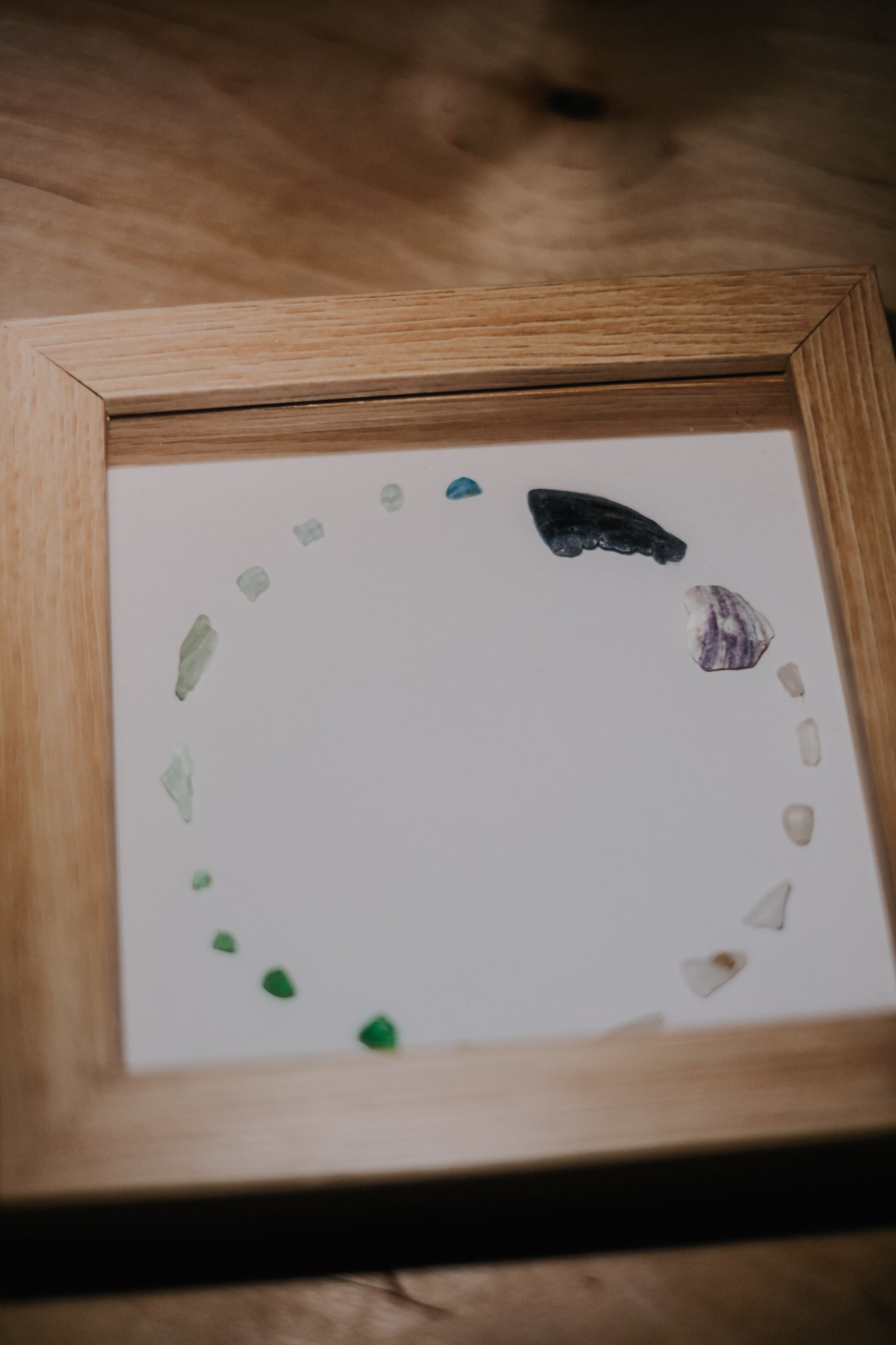 Framed artwork with natural elements on a wooden surface