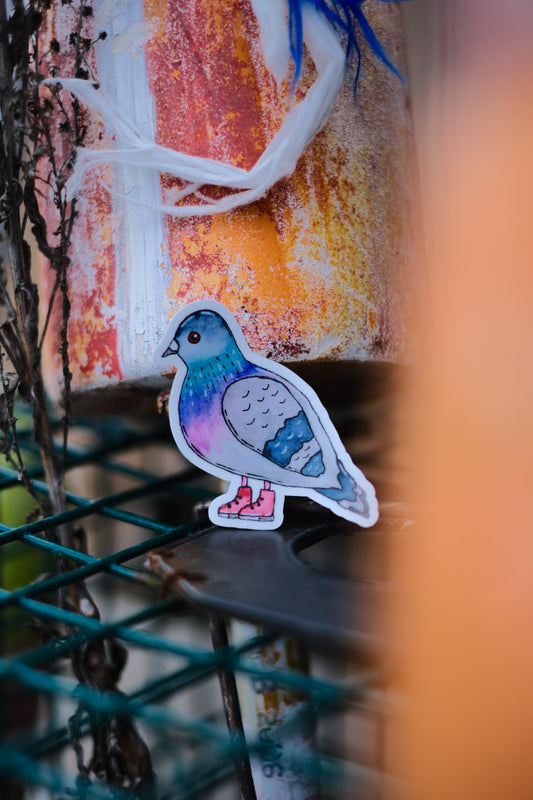 Colorful pigeon sticker on a textured surface with blurred background