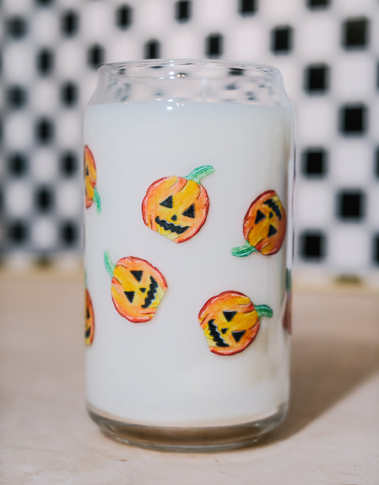 Glass filled with soy wax with pumpkin designs on a white background